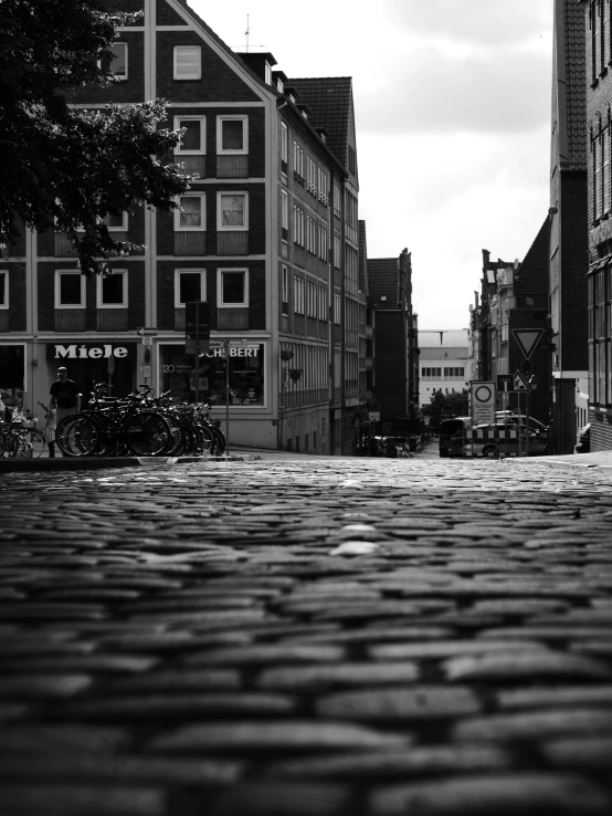 a black and white photo of a cobblestone street, by Tobias Stimmer, city in backround, low angle!!!!, michal mraz, germany