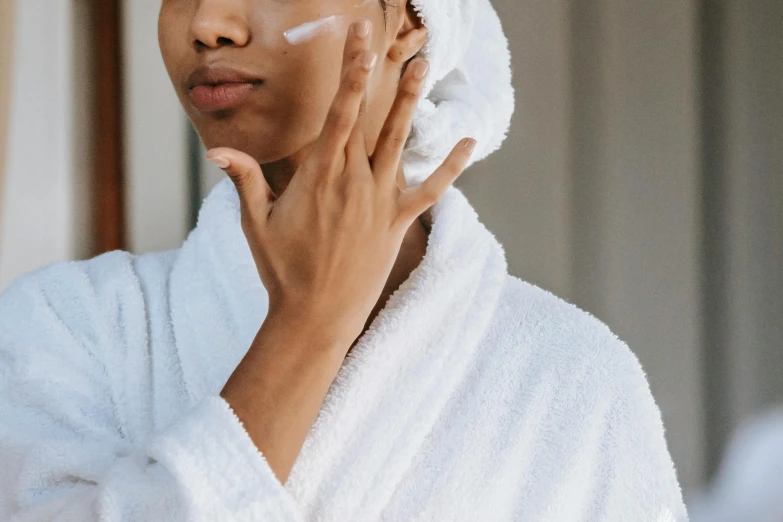 a woman is shaving her face with a towel, by Emma Andijewska, trending on pexels, renaissance, square facial structure, wearing a robe, manuka, ad image
