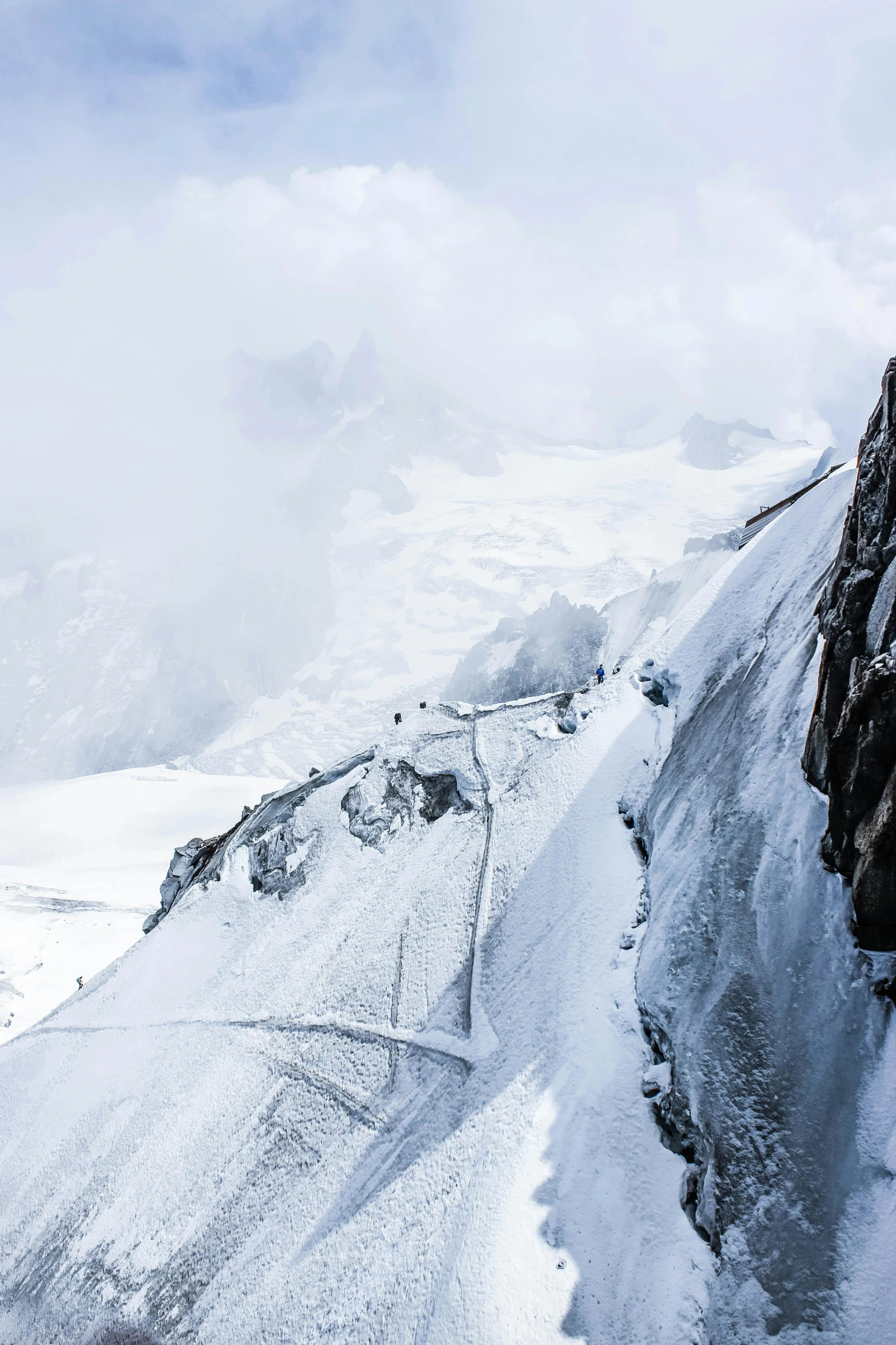 a man standing on top of a snow covered mountain, lauterbrunnen valley, tiny people walking below, a gigantic wall, 8k resolution”