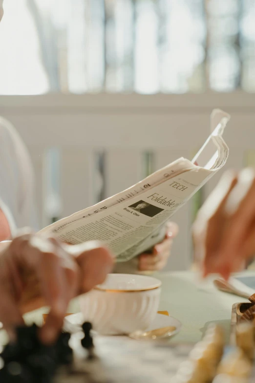 a couple of people that are sitting at a table, pexels contest winner, private press, reading the newspaper, table set for second breakfast, up close shot, zoomed in