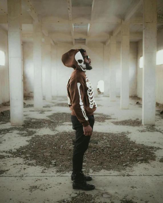 a man wearing a skeleton mask standing in an empty building, an album cover, unsplash contest winner, afrofuturism, brown and white color scheme, wearing a bomber jacket, taken in the late 2010s, skeleton pirate