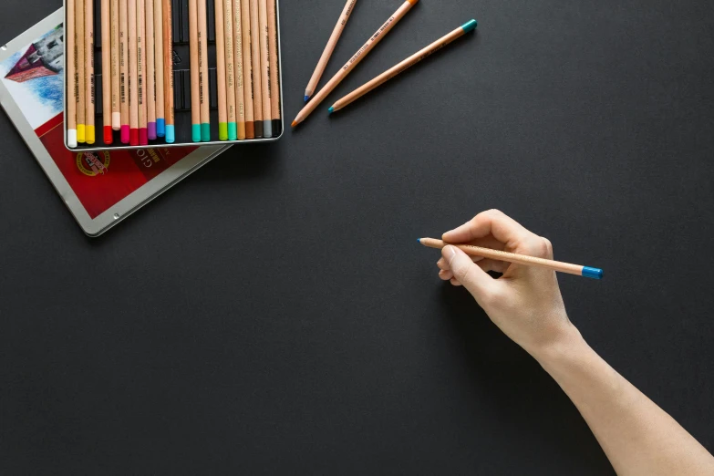 a person drawing with colored pencils on a black surface, inspired by Gerard David, pexels contest winner, blackboard in background, website banner, educational supplies, minimalistic drawing