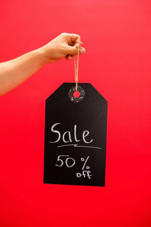 a hand holding a sale tag on a red background, trending on unsplash, blackboard, square, dark. no text, 50