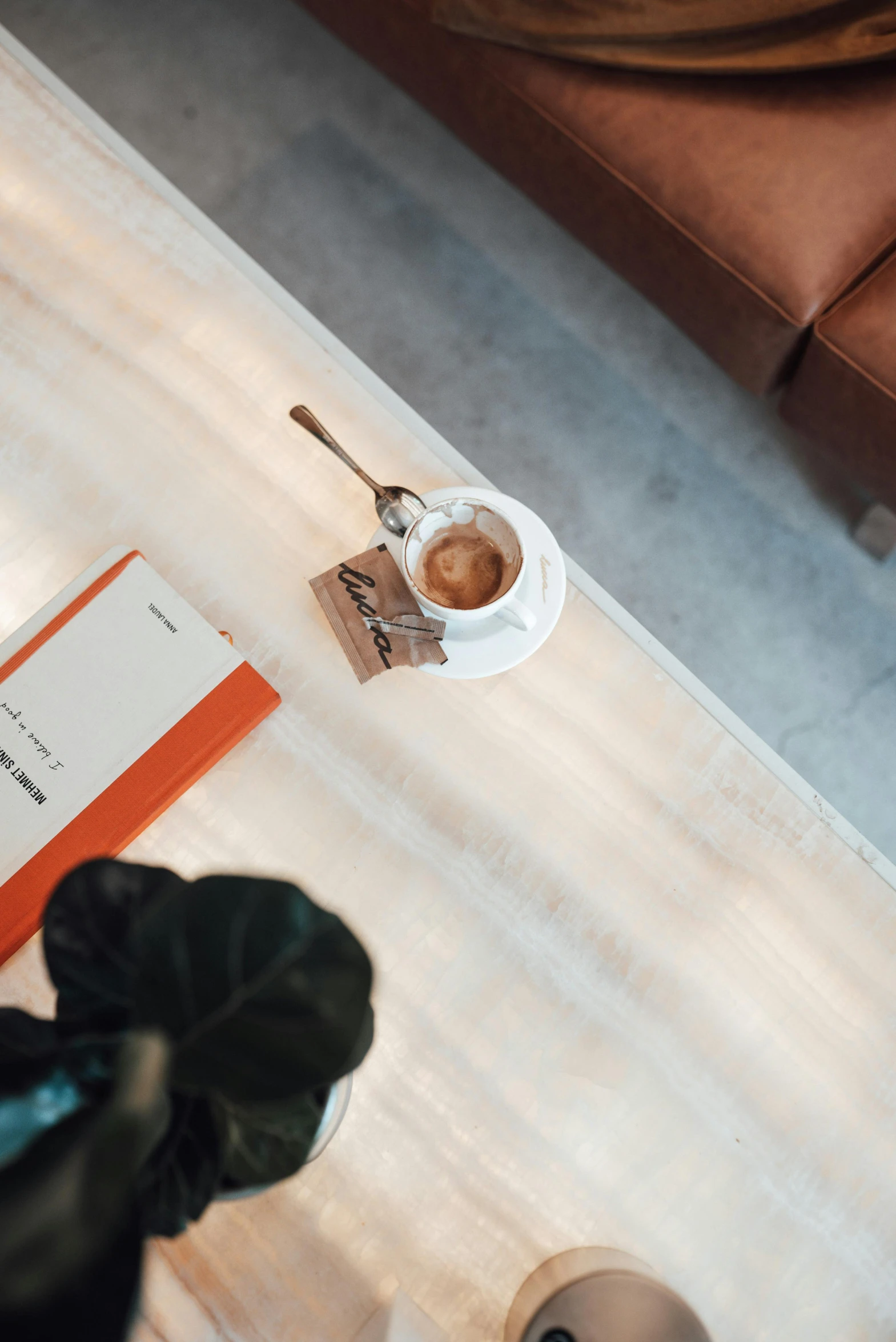 a person sitting at a table with a cup of coffee, marble table, sitting in a waiting room, flatlay book collection, brown and white color scheme