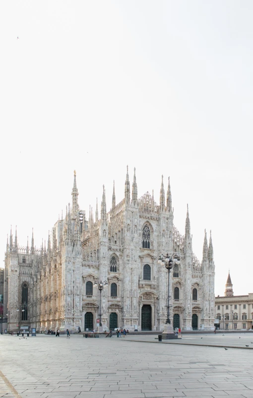 a man sitting on a bench in front of a cathedral, by Carlo Martini, pexels contest winner, panorama view, milan schere, white building, silver and yellow color scheme