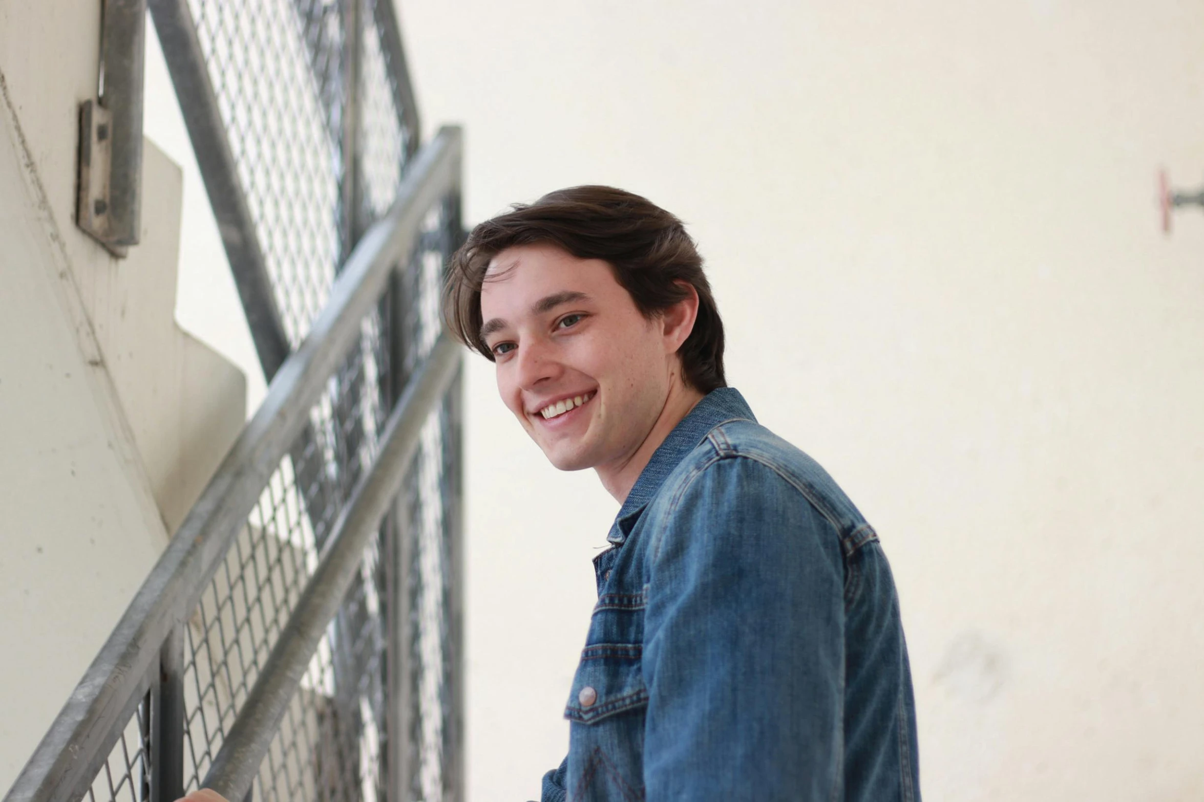 a man standing at the top of a set of stairs, a portrait, pexels contest winner, happening, smiling slightly, ethan klein, in front of white back drop, student
