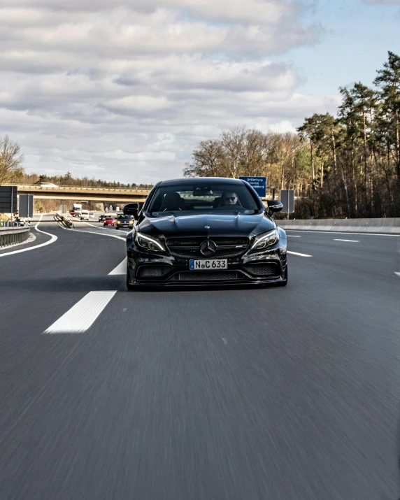 a car driving down a highway on a cloudy day, by Adam Marczyński, mercedez benz, wide body, thumbnail, profile image