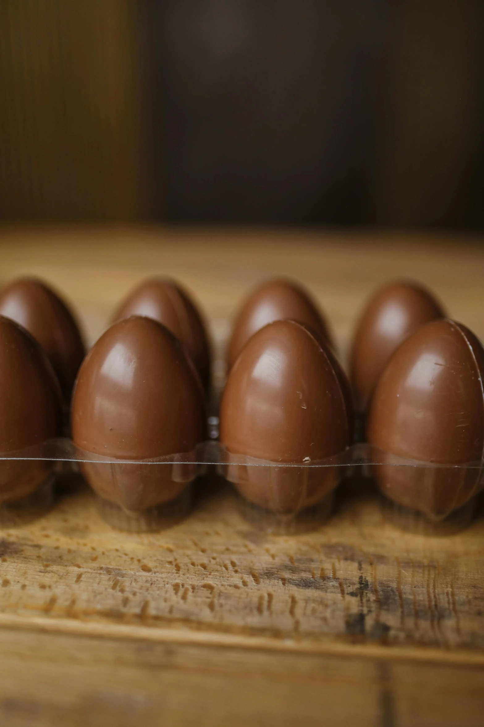 a group of chocolate eggs sitting on top of a wooden table, in a row, hull, thumbnail, 8 x