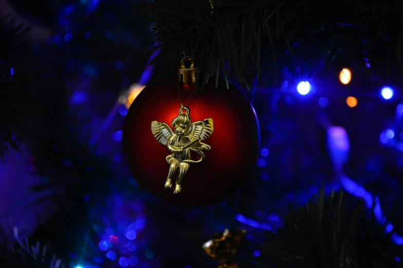 a christmas ornament hanging from a christmas tree, pexels, renaissance, angels and demons, light red and deep blue mood, shot on sony a 7 iii, tiny faeries