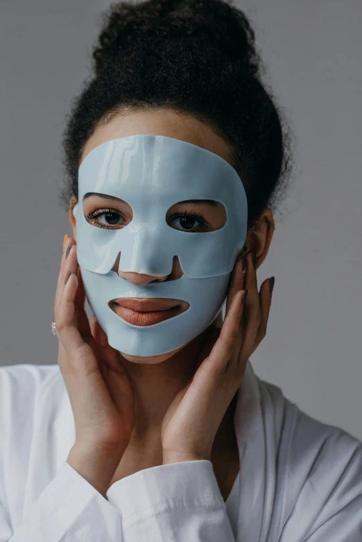 a woman with a blue mask on her face, on grey background, featured face details, soft face features, made of lab tissue