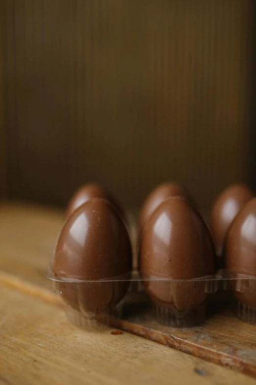 a group of chocolate eggs sitting on top of a wooden table, in a row, upclose, けもの, short dof