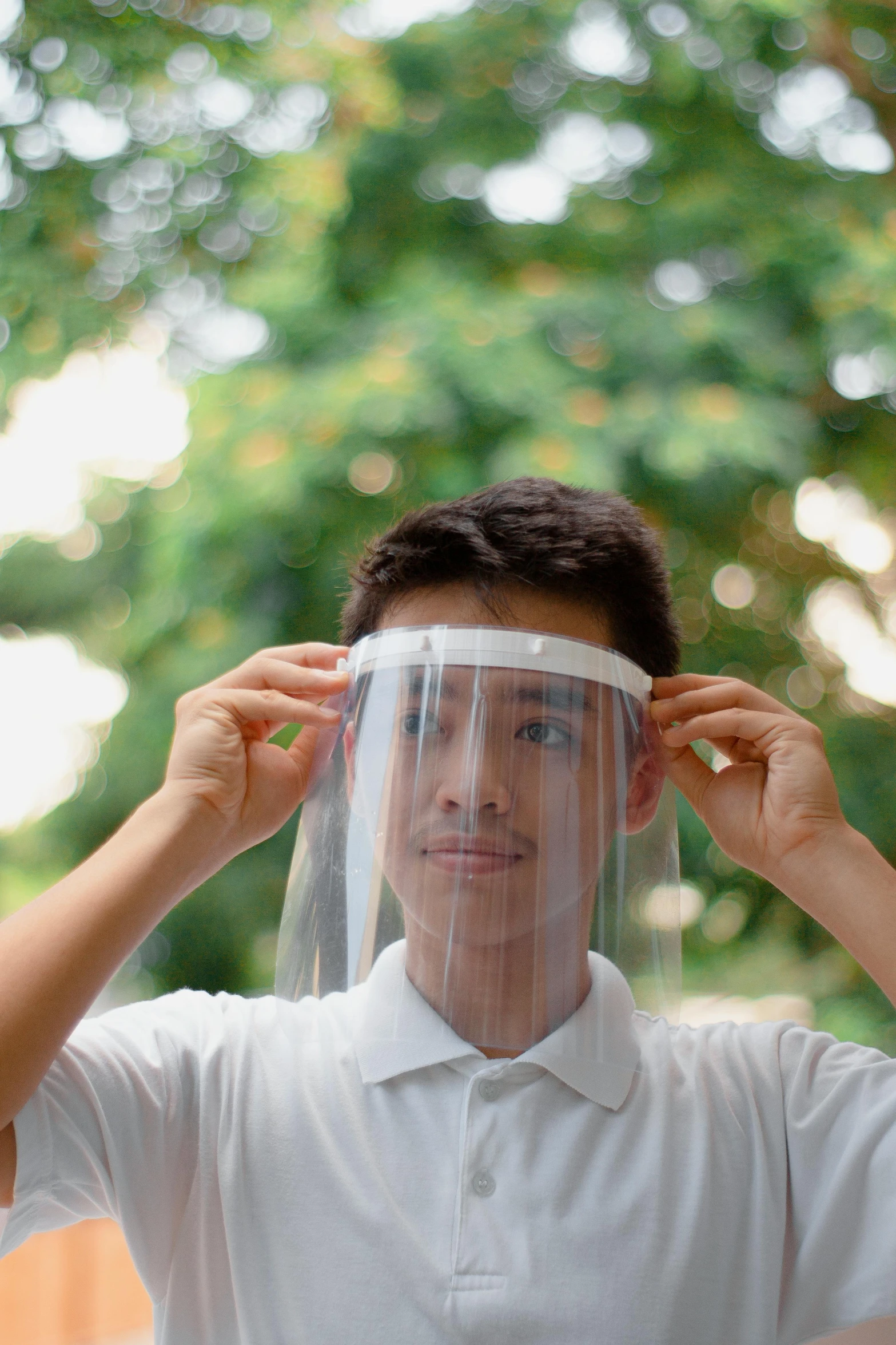 a man putting a face shield on his head, an album cover, trending on pexels, plasticien, singapore, teen boy, 3/4 front view, wide film still