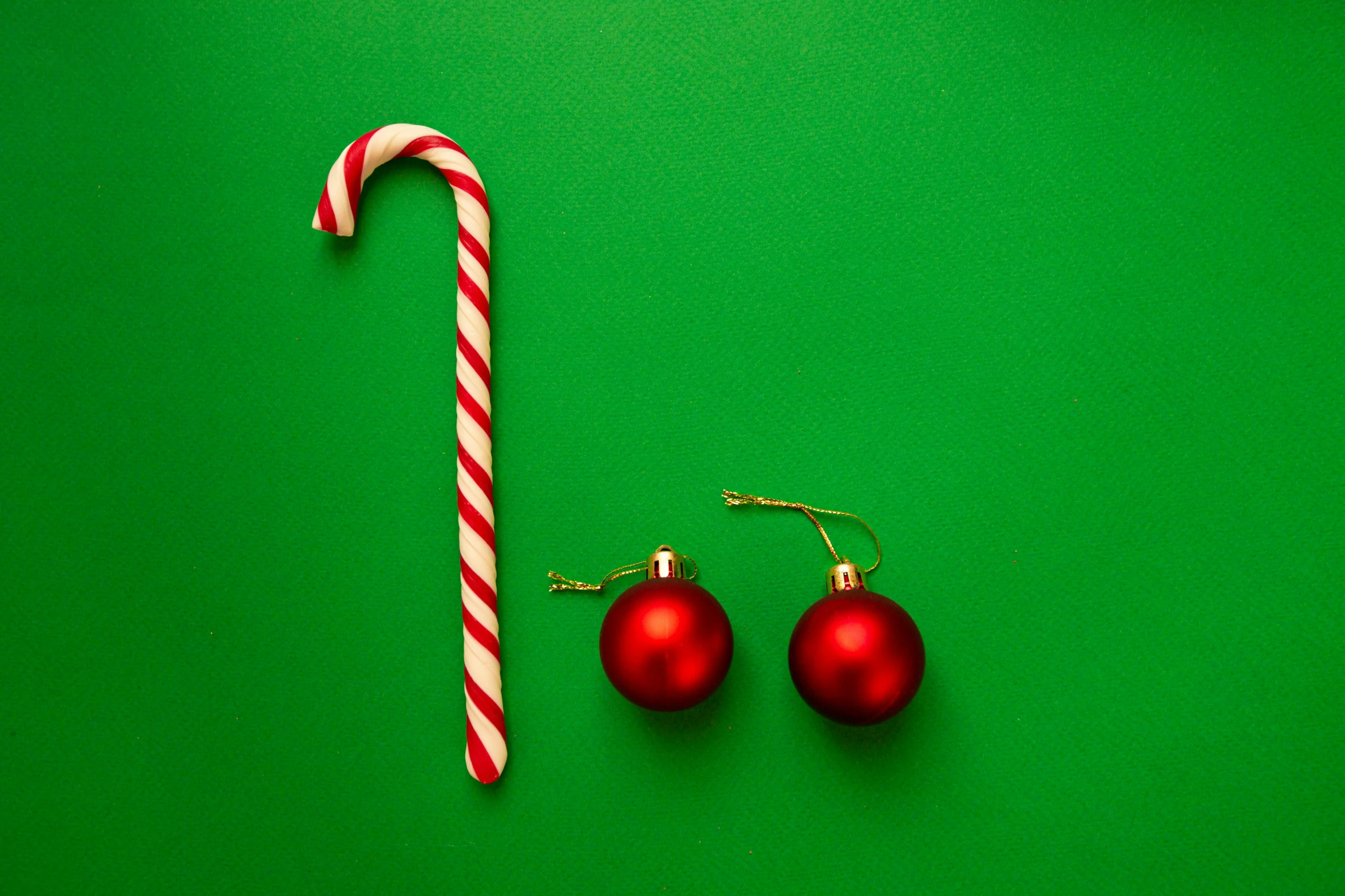 a candy cane and two ornaments on a green surface, by Emma Andijewska, pexels, minimalism, shepherd's crook, square, red colour palette, with lots of thin ornaments
