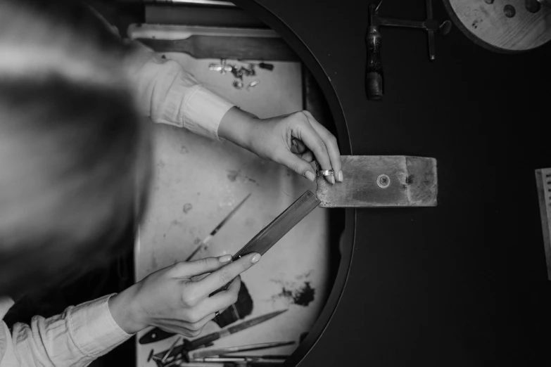 a black and white photo of a person cutting a piece of wood, arbeitsrat für kunst, van cleef & arpels style, high quality upload, ✨🕌🌙, studio ghibi