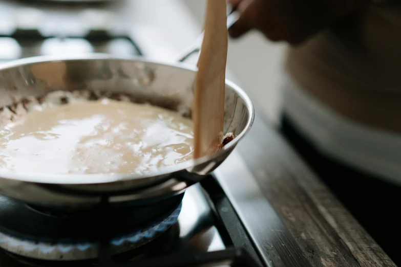 a person stirring something in a pot on a stove, trending on unsplash, process art, cream, background image, brown gravy, pastry