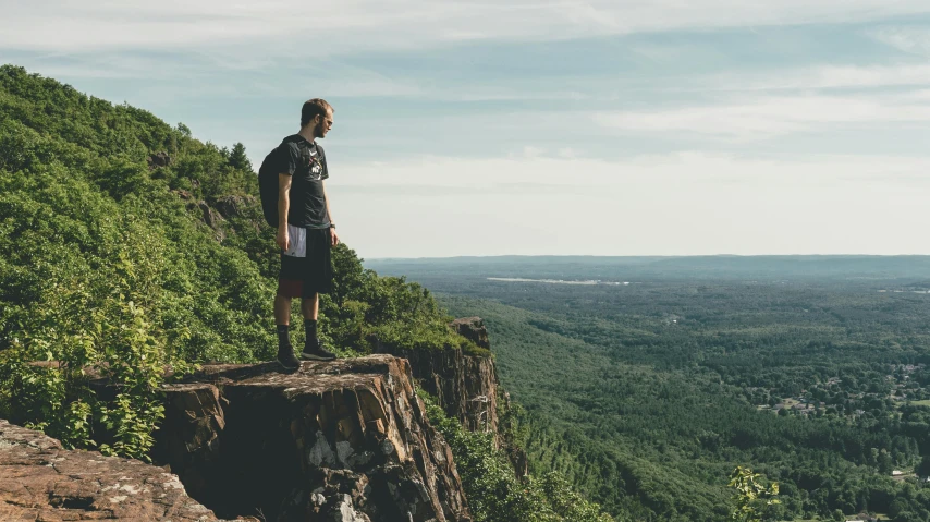 a man standing on a cliff overlooking a valley, quebec, avatar image, outdoor photo