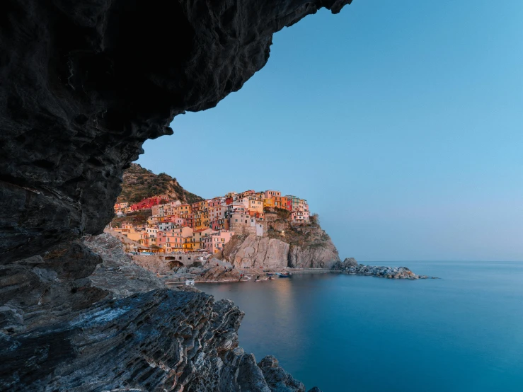 a view of a small town from a cave, by Carlo Martini, pexels contest winner, hyperrealism, cinq terre, medium format color photography, evening light, multicoloured