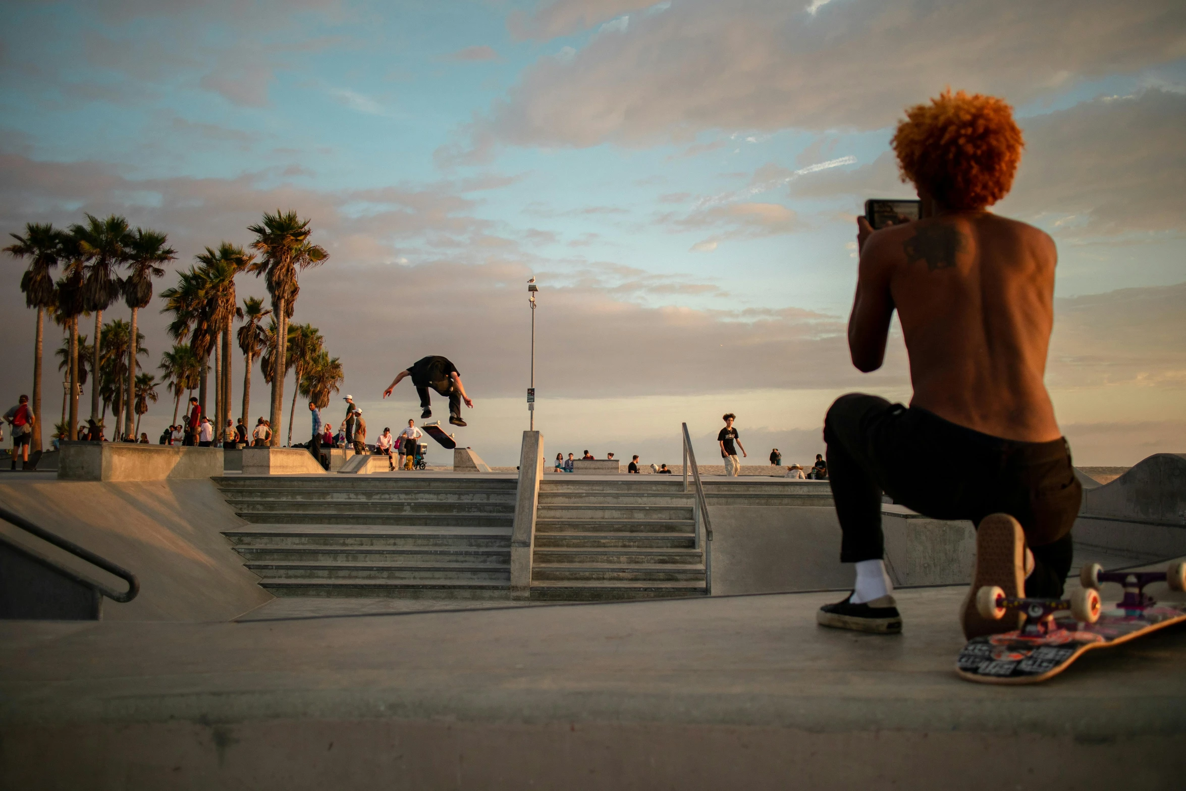 a man riding a skateboard up the side of a ramp, a picture, by Leo Michelson, unsplash contest winner, in a beachfront environment, benches, los angelos, late summer evening