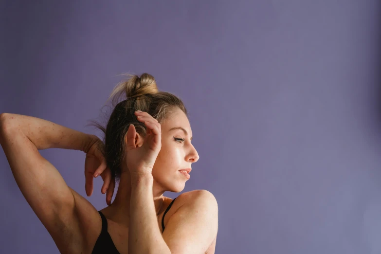 a woman standing in front of a purple wall, trending on pexels, arabesque, portrait of a ballerina, background image, head and body, hands in her hair. side-view