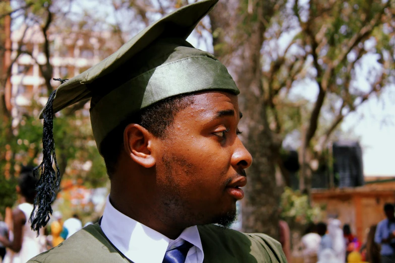 a man wearing a graduation cap and gown, a photo, by Stokely Webster, green hood, mongezi ncaphayi, look at the details, unedited