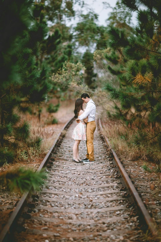 a man and woman standing on a train track, pexels contest winner, romanticism, lying on the woods path, lovely kiss, & all the world around you, pretty