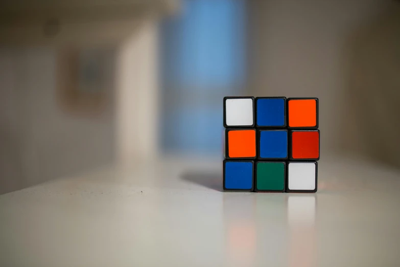 a rubik cube sitting on top of a table, inspired by Ernő Rubik, unsplash, square, medium - shot, coloured, nostalgic 8k