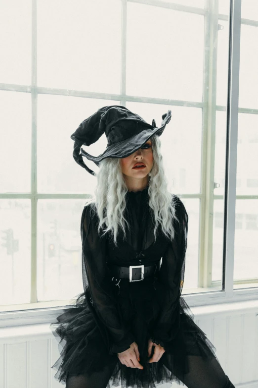 a woman in a witch costume sitting on a window sill, an album cover, trending on pexels, flowy white grey hair, black hat, gif, dnd)