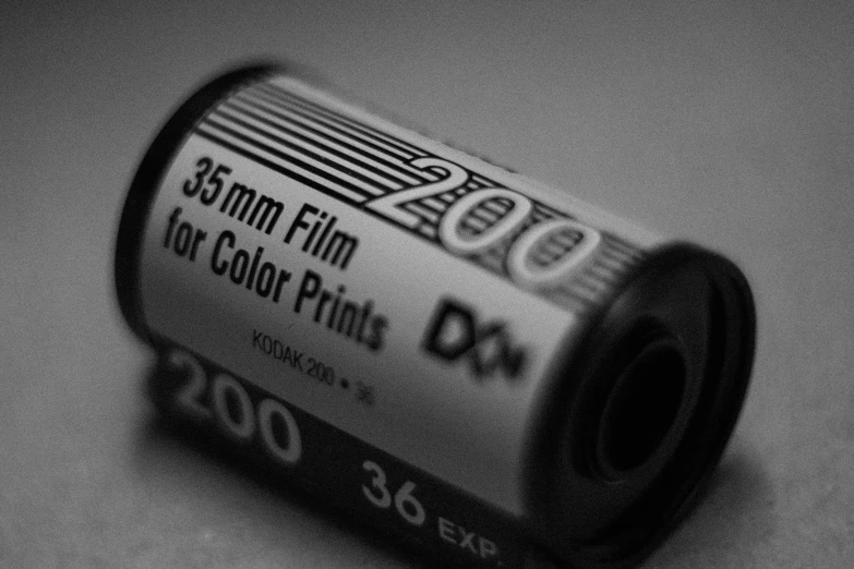 a roll of film sitting on top of a table, by Adam Chmielowski, colored accurately, black and white color, 35mm film!!!!!!!!