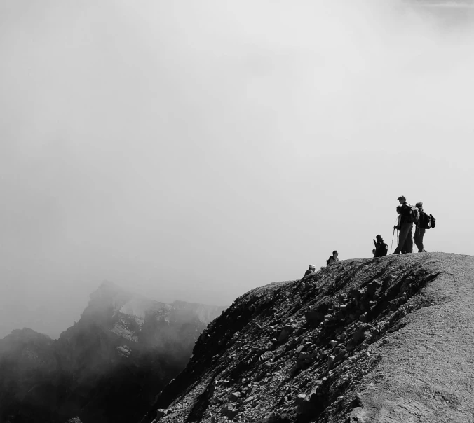 a group of people standing on top of a mountain, a black and white photo, pexels contest winner, minimalism, smokey atmosphere, people angling at the edge, photographic print