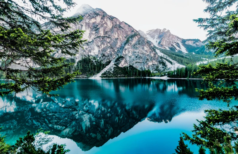 a lake surrounded by trees with mountains in the background, pexels contest winner, mirror and glass surfaces, blue waters, multiple stories, peak