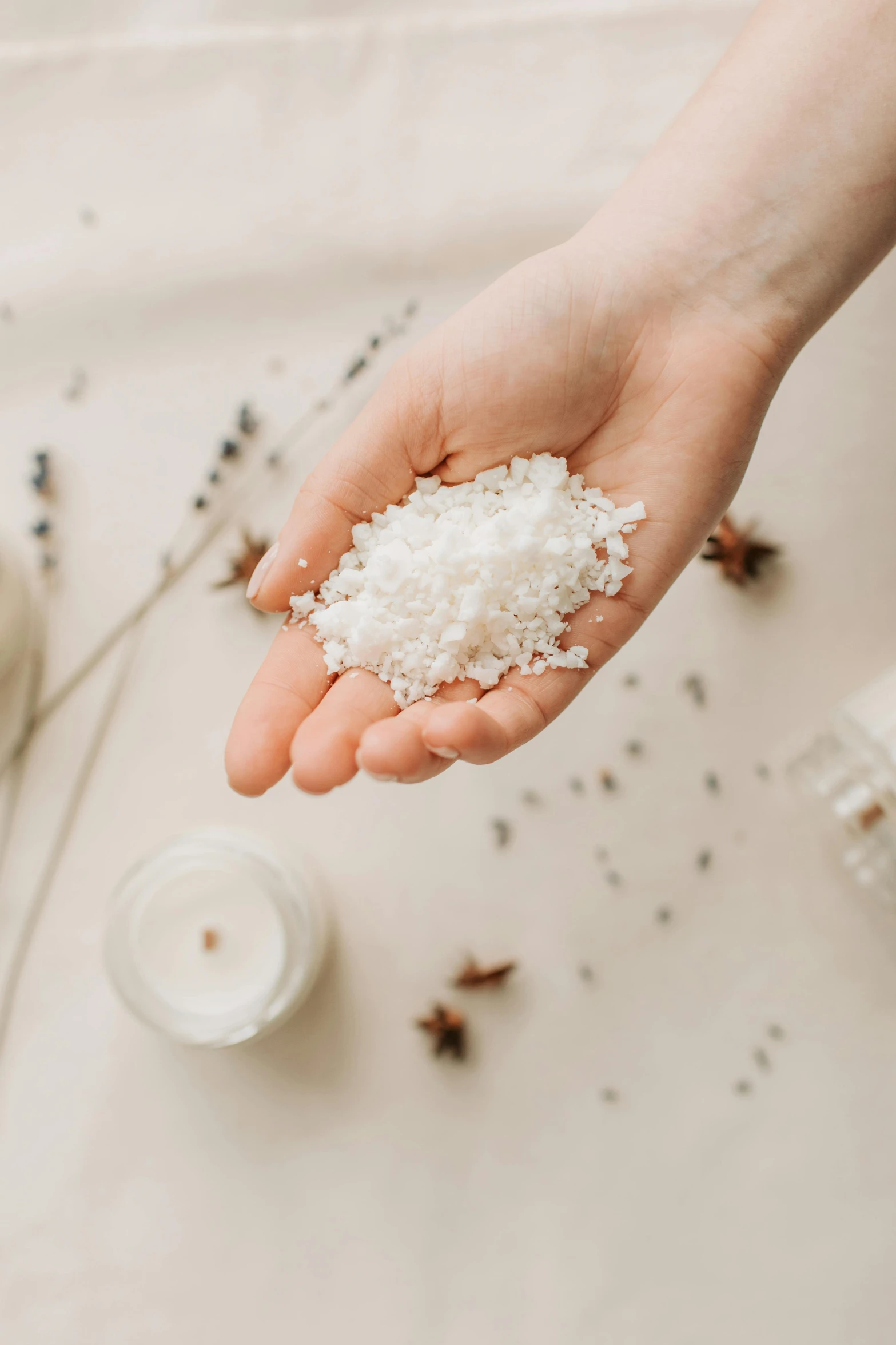 a person holding a handful of rice in their hand, trending on pexels, plasticien, white candles, salt effects, botanicals, crushed