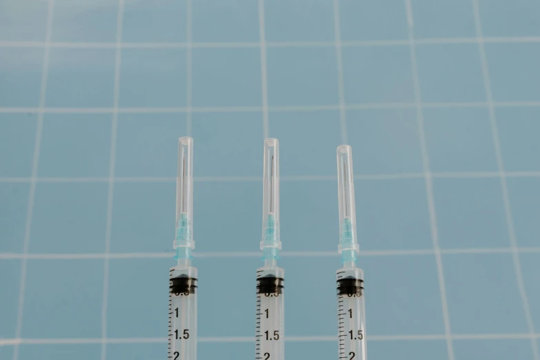 three sylls sitting next to each other on a table, an album cover, unsplash, syringes, with a blue background, highly microdetailed, medical image