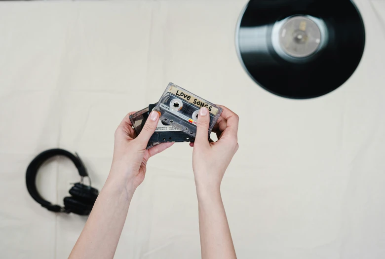 a close up of a person holding a camera, an album cover, unsplash, tape deck, performing, lena oxton, on a white table