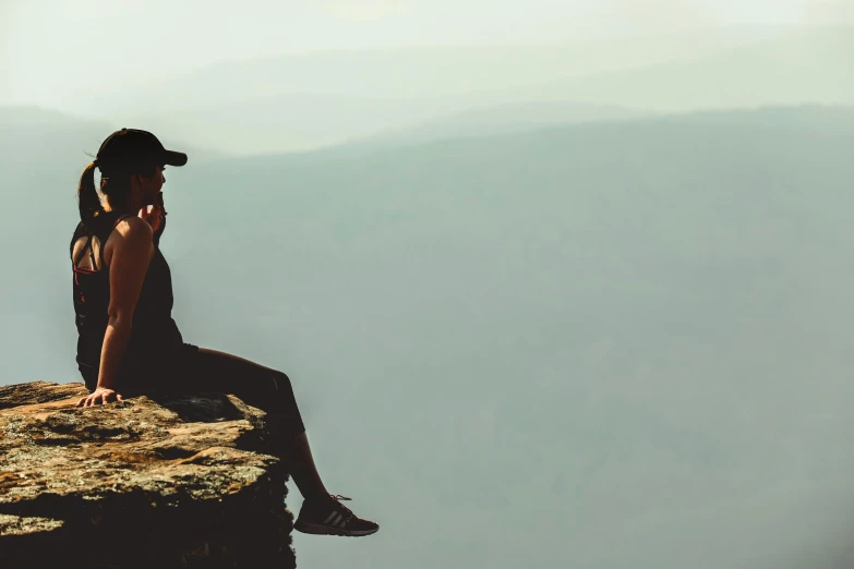 a woman sitting on the edge of a cliff, pexels contest winner, black, girl making a phone call, sad man, wearing sunglasses and a cap