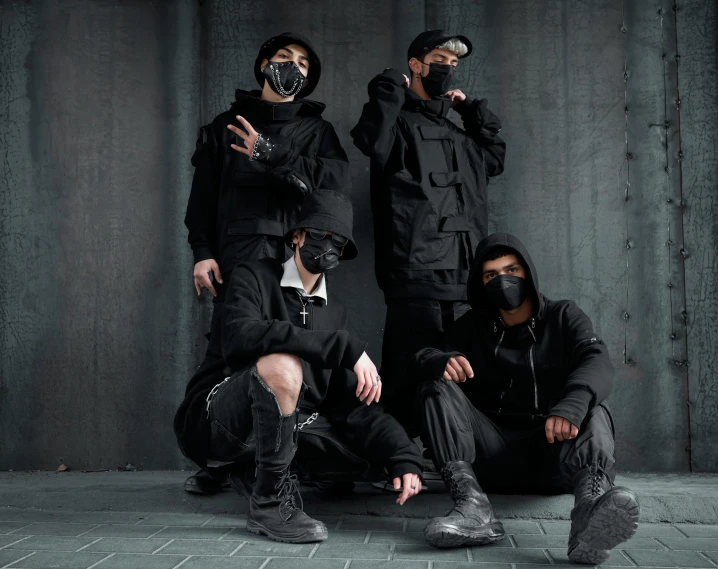 a group of men sitting next to each other, an album cover, trending on pexels, sots art, techwear occultist, wearing all black mempo mask, tactical vests and holsters, stylish pose