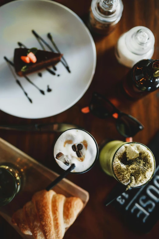 a table topped with plates of food and drinks, iced latte, green and black colors, thumbnail, cake