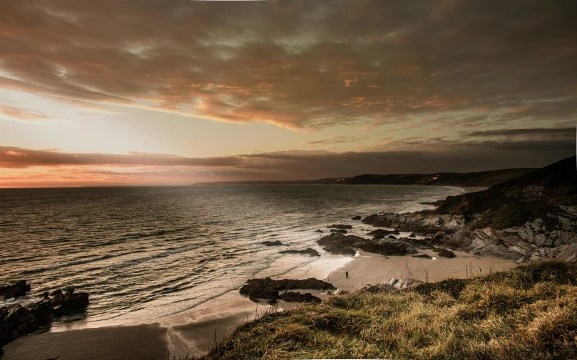 a sunset over a beach and a body of water, pexels contest winner, cornwall, slide show, grey, brown