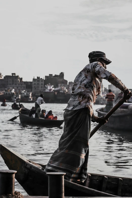 a man in a boat on a body of water, pexels contest winner, process art, old dhaka, split near the left, carson ellis, grey