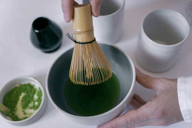 a person holding a whisk in a bowl of green tea, inspired by Kanō Shōsenin, spray brush, medium close up, grey, jade green