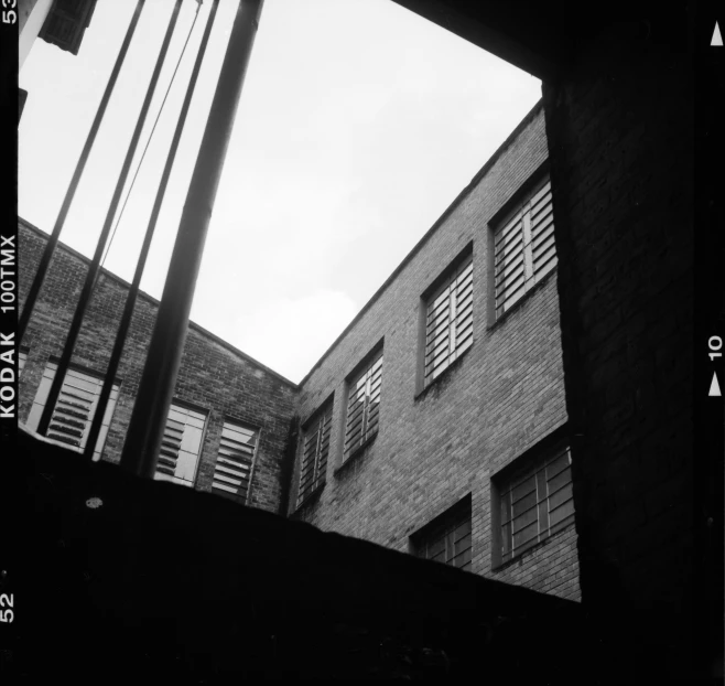 a black and white photo of a window in a building, by Maurycy Gottlieb, school courtyard, view from bottom, agfa film, unknown title