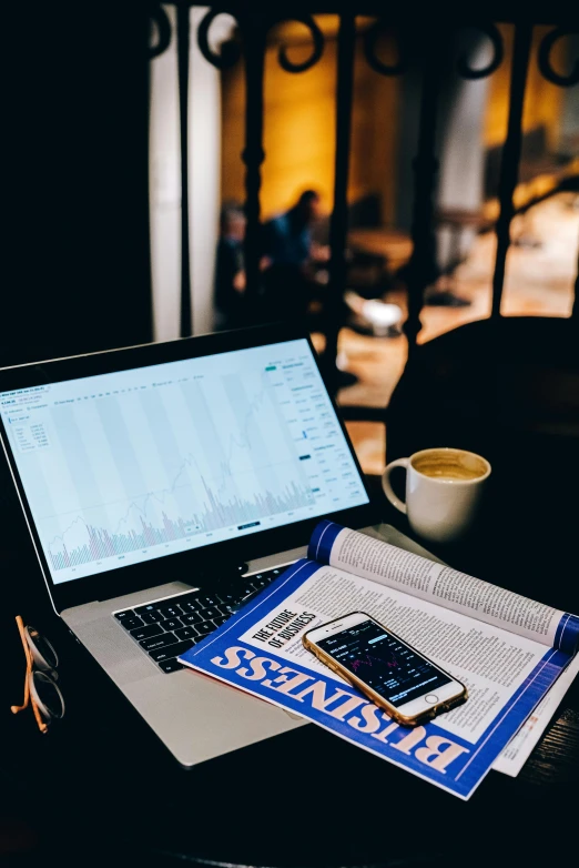 a laptop computer sitting on top of a table next to a cup of coffee, by Sebastian Vrancx, trending on unsplash, happening, displaying stock charts, reading the newspaper, studious, phone photo