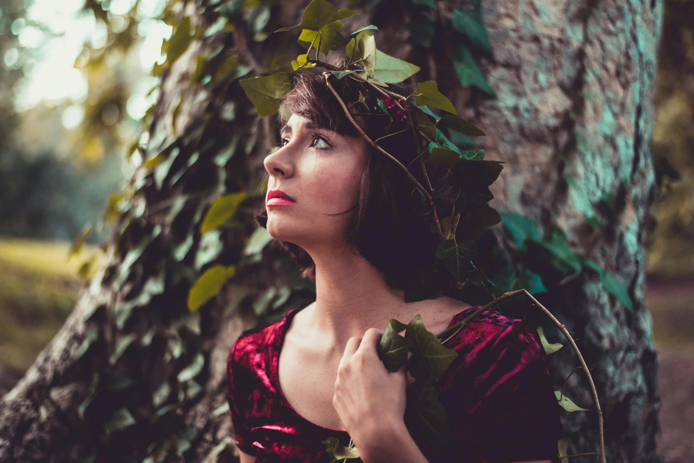 a woman in a red dress standing next to a tree, inspired by Elsa Bleda, pexels contest winner, renaissance, dressed in laurel wreath, young woman looking up, ivy, avatar image