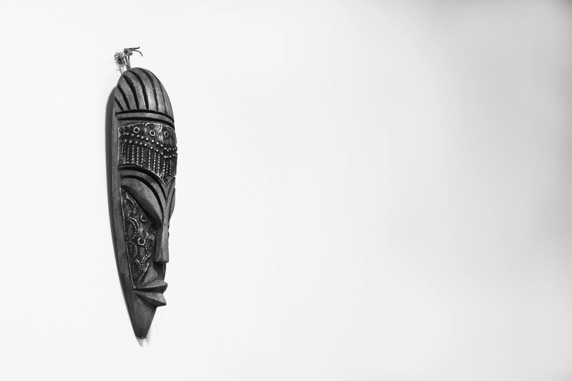 a black and white photo of a kite flying in the sky, an abstract sculpture, trending on pexels, hurufiyya, west africa mask patterns style, white background wall, sculpture made of wood, portrait of a old