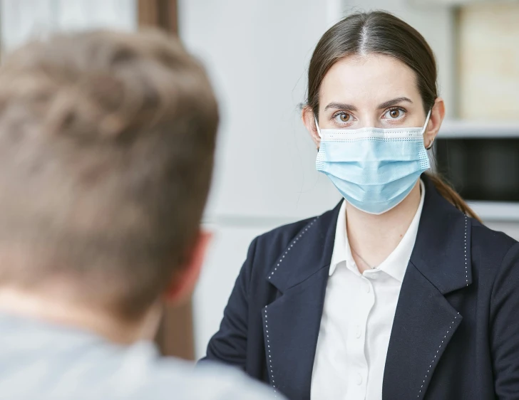 a woman wearing a face mask talking to a man, trending on pexels, lachlan bailey, local conspirologist, staff, over the shoulder