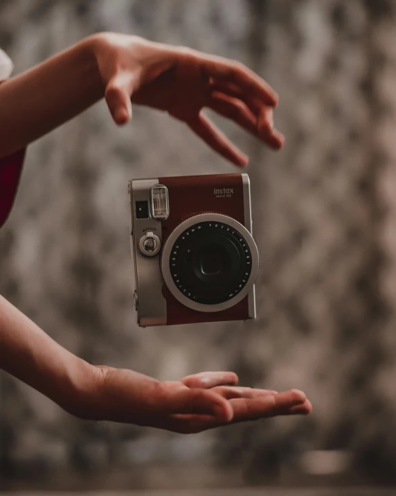 a person holding a camera in their hand, a polaroid photo, by Julia Pishtar, pexels contest winner, hovering in the air, red camera, flash photo, pose(arms up + happy)