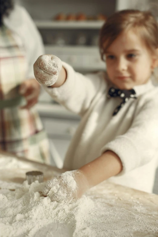 a little girl that is standing in the kitchen, inspired by Elsa Beskow, pexels, process art, covered in white flour, white gloves, school class, blurred