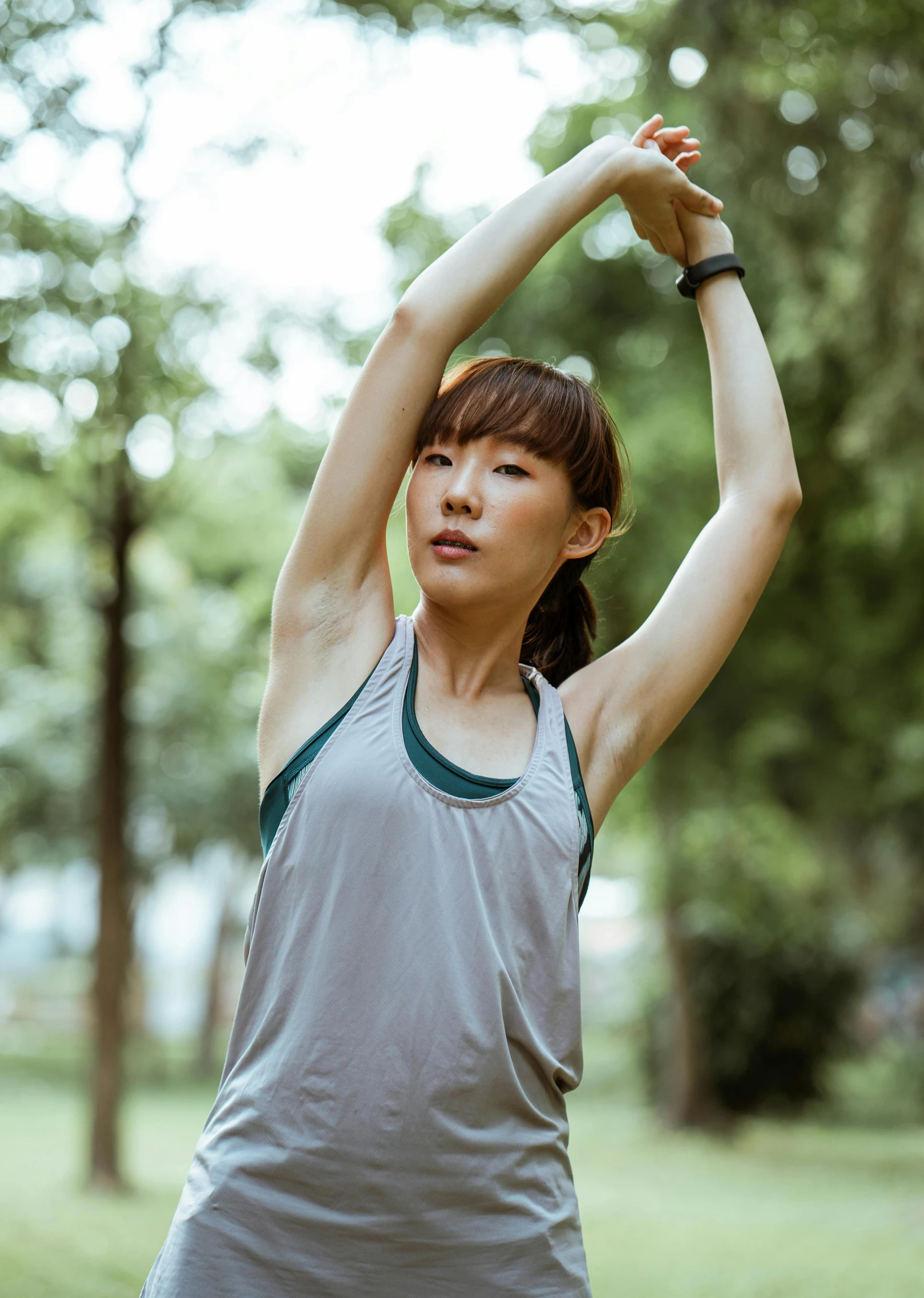 a woman doing a yoga pose in a park, by Jang Seung-eop, wearing : tanktop, dynamic active running pose, grey, armpit