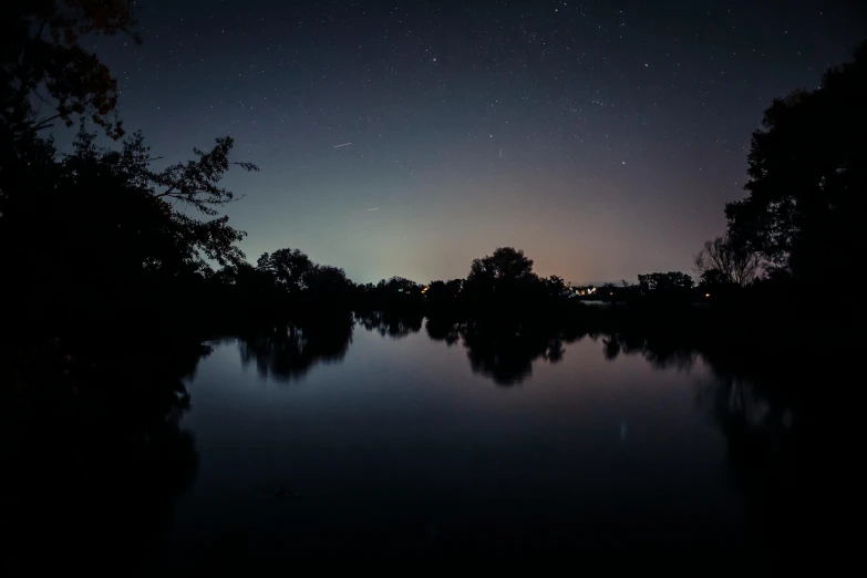 a body of water surrounded by trees at night, a picture, by Adam Szentpétery, hurufiyya, planets align, reflective gradient, poorly lit, today\'s featured photograph 4k