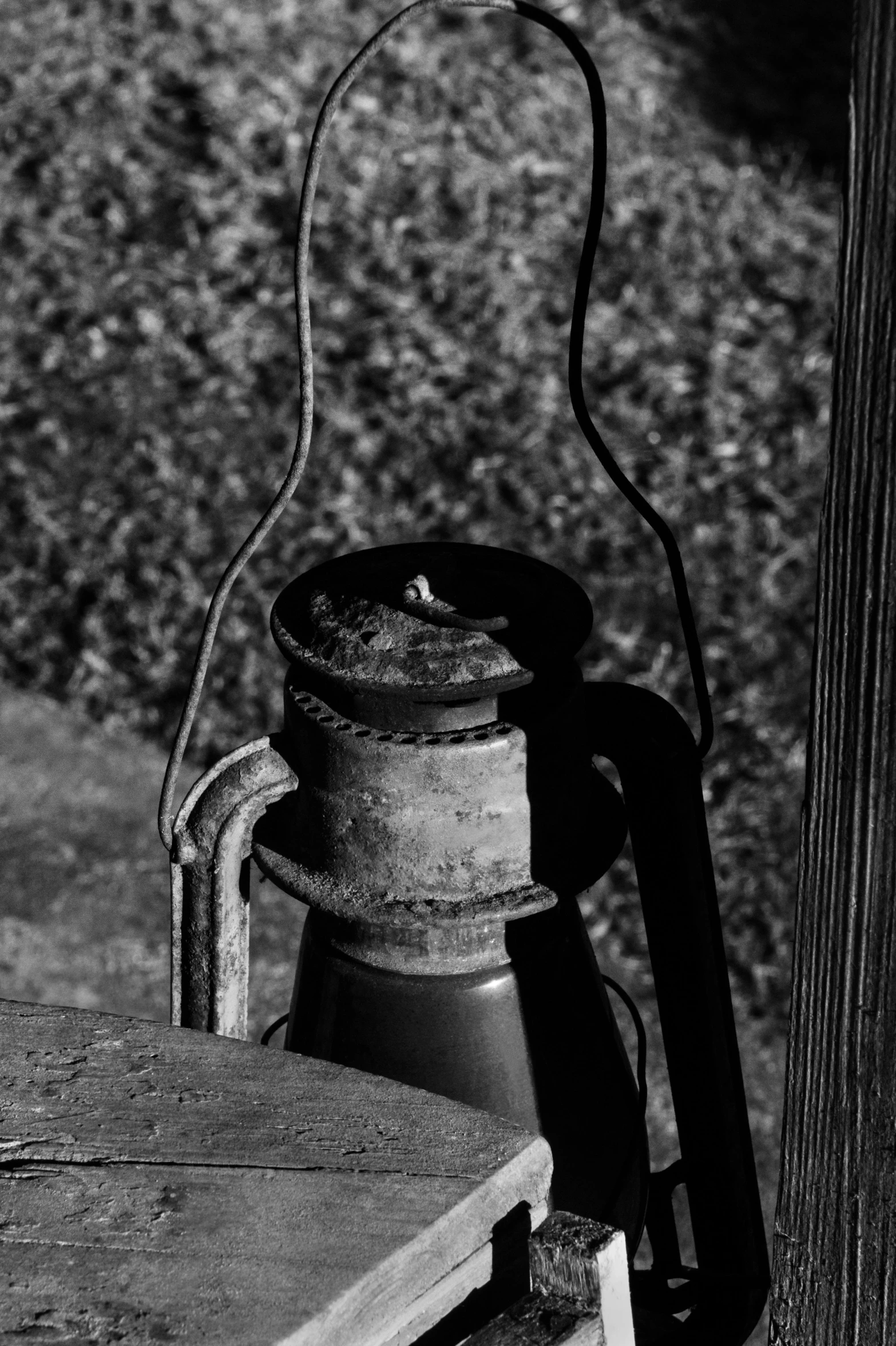 a lantern sitting on top of a wooden table, inspired by Roy DeCarava, kettle, rusty, black white, detail