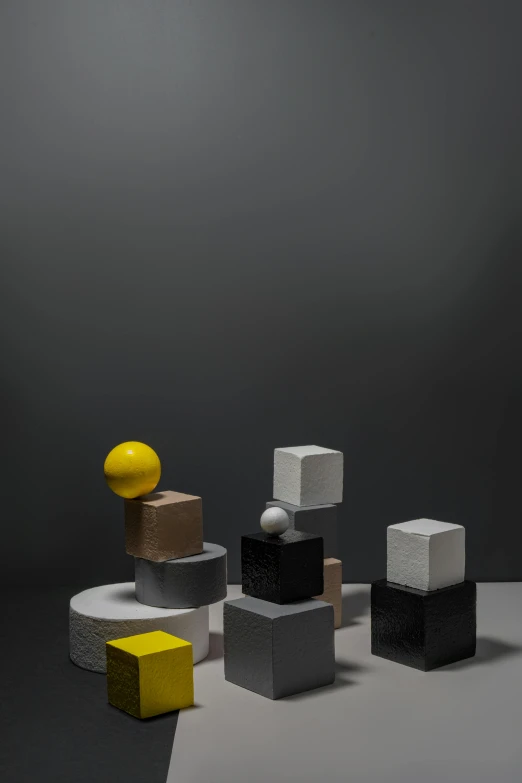 a group of cubes sitting on top of a table, an abstract sculpture, inspired by Bauhaus, charcoal and yellow leather, spheres, paul barson, full product shot